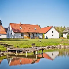 Domki z czerwonymi dachami nad jeziorem, z pomostem i ławką.